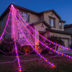 Giant Halloween spider web lights stretched over the front yard of a house at dusk