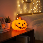 Ghost face pumpkin lamp glowing on a bedroom shelf at night