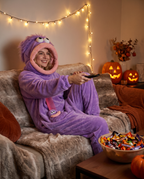 Person in monster onesie relaxing on couch on Halloween movie night